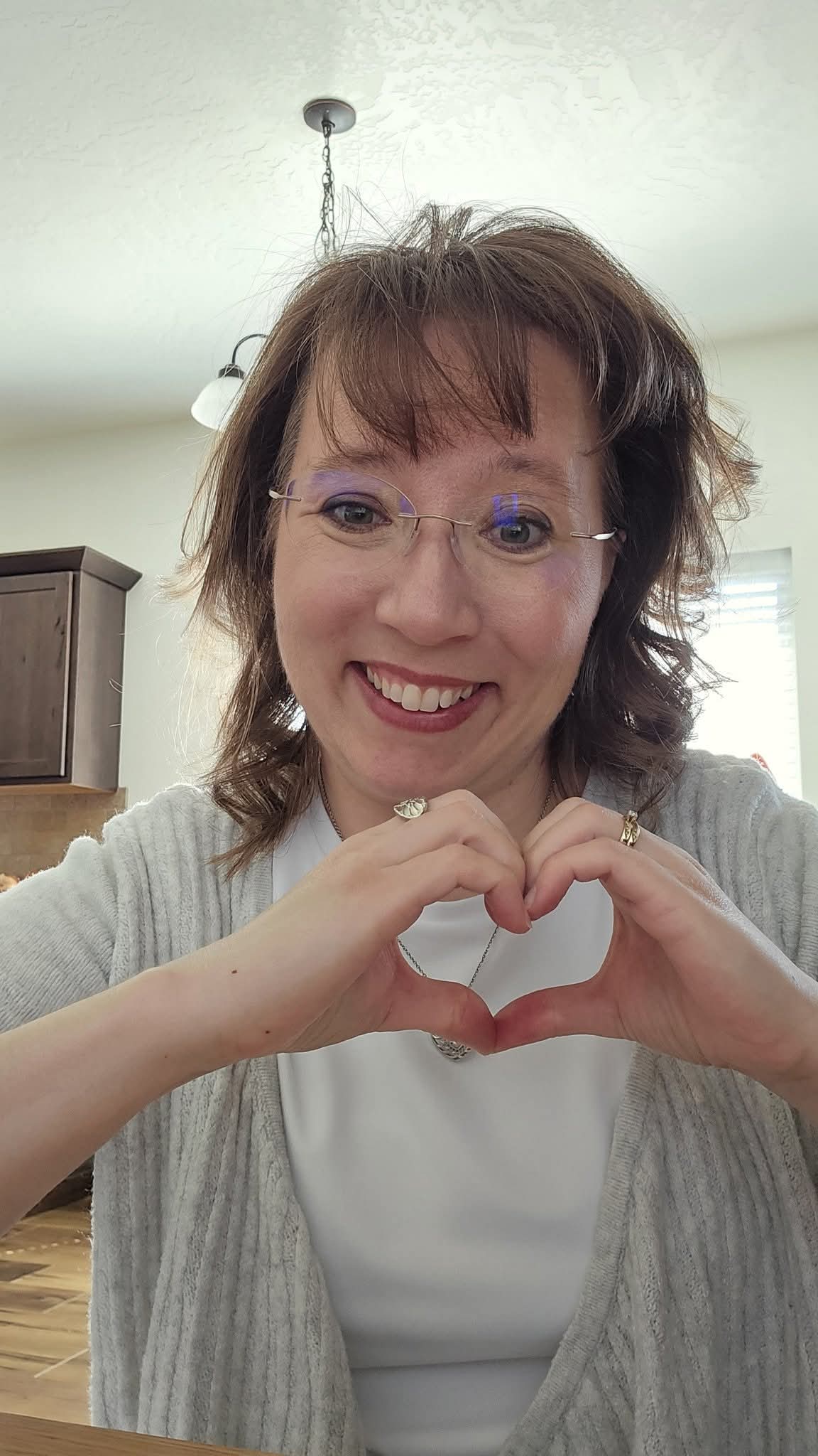 Emmaline Hoffmeister making a heart shape with her hands. I love n readers.