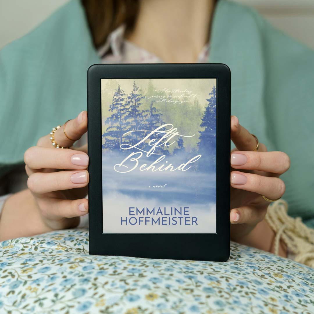 A woman wearing rings and holding an eBook copy of Left Behind by Emmaline Hoffmeister. Left Behind is an LDS Christian fiction novel by LDS author Emmaline Hoffmeister.